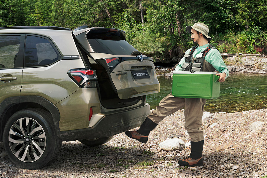 Subaru ar brīvroku bagāžas nodalījuma atvēršanu – vīrietis makšķerēšanas ekipējumā aktivizē sensoru ar kāju, lai atvērtu bagāžnieku bez rokām.
